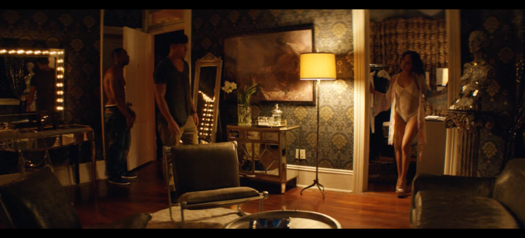 Figure 6. The Southern Gothic interior of Domina. Magic Mike XXL, author’s screenshot. An ornately decorated and furnished set of rooms, with southern, modern, and victorian influences, shows three standing figures in various states of undress. They appear to be getting ready to perform.