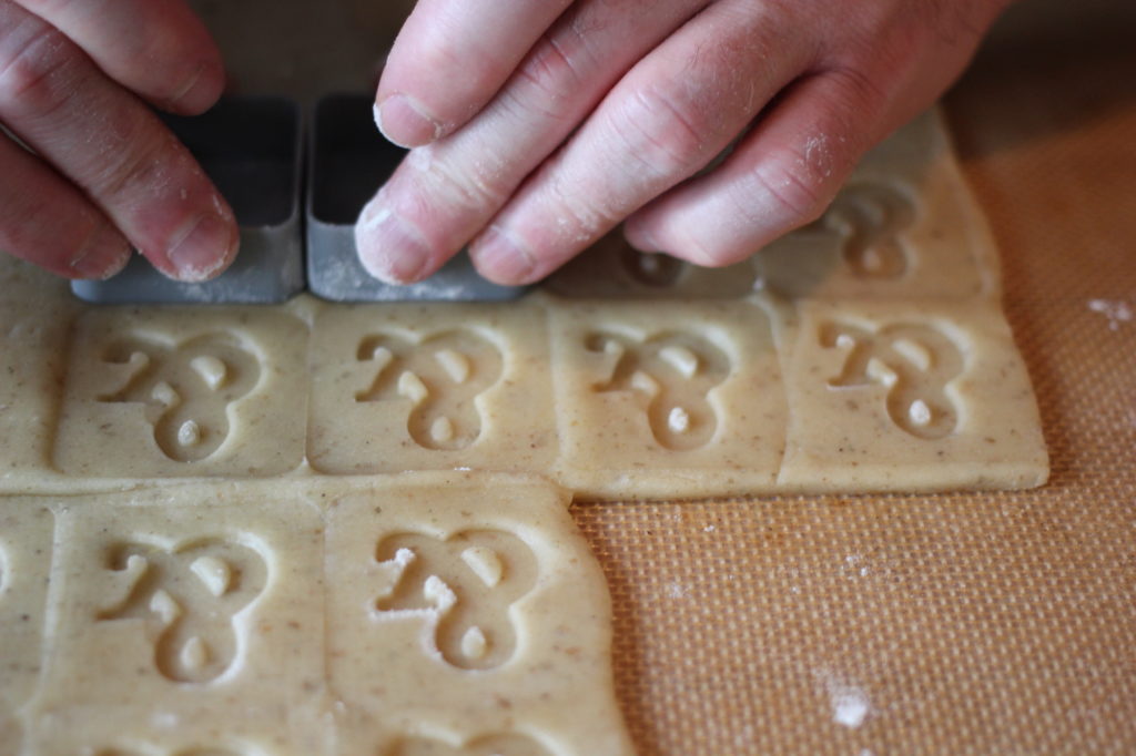 Close up photo of hands stamping an ampersand on squares of dough.