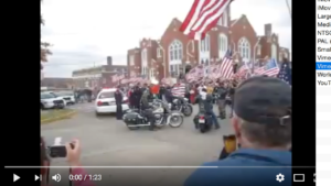 Fig. 6. kolfan93. Westboro Baptist Church meets BACA and other bikers McAlester, OK source: “Blue Iron Texas Original LEMC Rolling Out. - YouTube.” N.p., n.d. Web. 1 Sept. 2017. https://www.youtube.com/watch?v=UoxhPL1B9qc. A screenshot of a youtube video shows people taking pictures of a group of motorcyclists who wield a large number of US American flags. They are gathered around an opulent building in white wood and red brick.