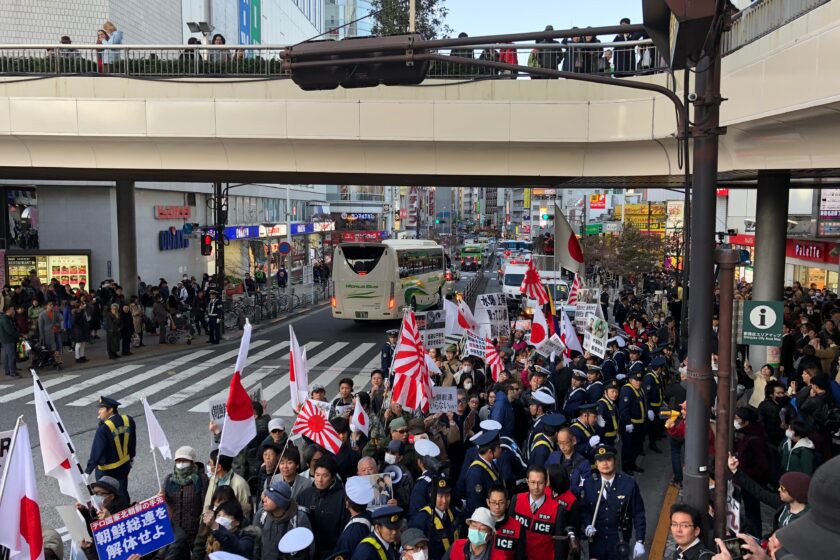 Right-wing protesters are gathered in the streets of Tokyo, flying the Japanese national flags as well as the Rising Sun Flags, which show red rays surrounding a red circle in the center, symbolizing the Sun. The latter design was adopted by the Imperial Japanese Army as a war flag during the World War II. Because it evokes Japanese war crimes, the design is controversial in Japan’s former colonies as well as for Allied WWII veterans.