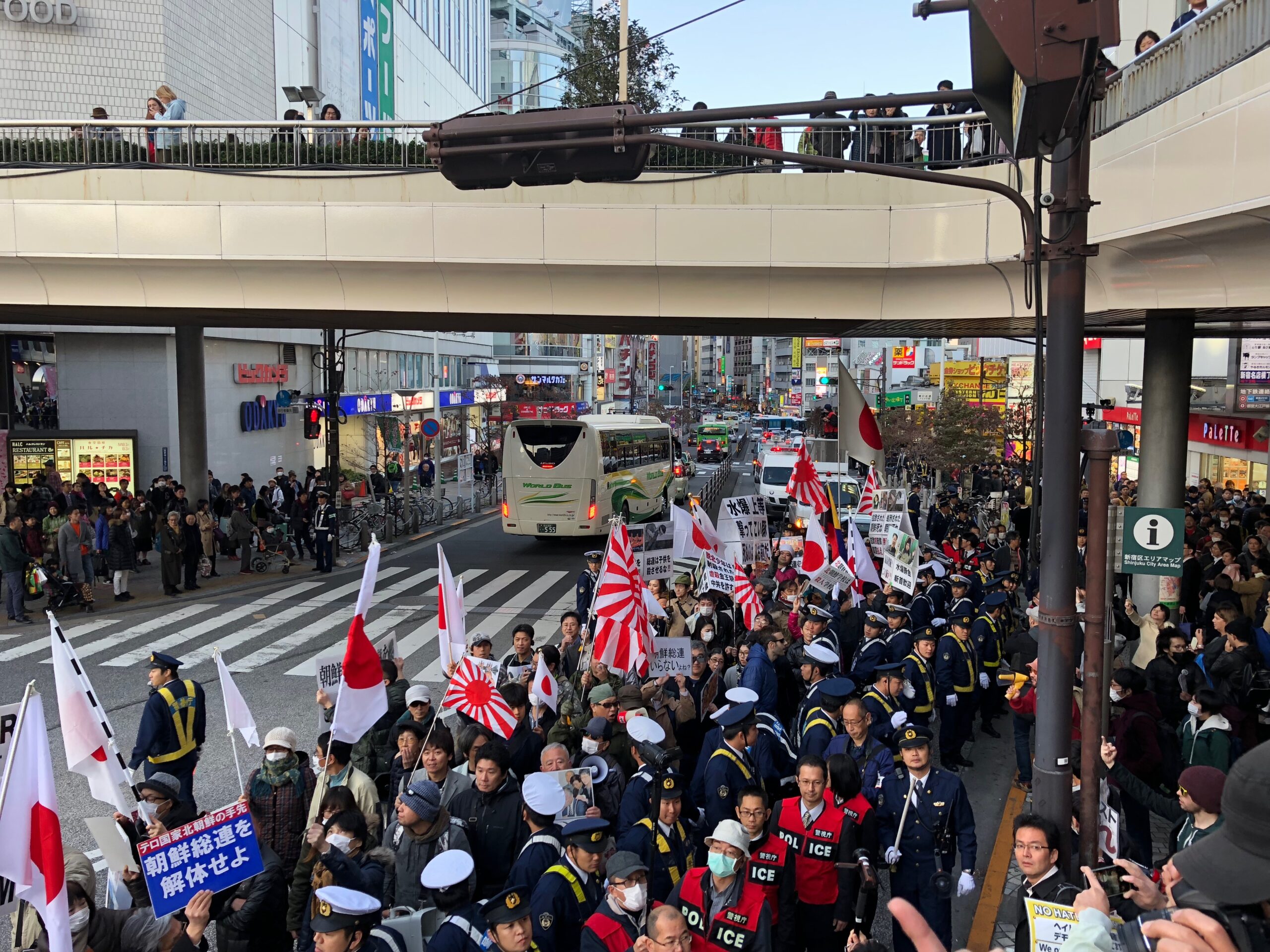 Right-wing protesters are gathered in the streets of Tokyo, flying the Japanese national flags as well as the Rising Sun Flags, which show red rays surrounding a red circle in the center, symbolizing the Sun. The latter design was adopted by the Imperial Japanese Army as a war flag during the World War II. Because it evokes Japanese war crimes, the design is controversial in Japan’s former colonies as well as for Allied WWII veterans.
