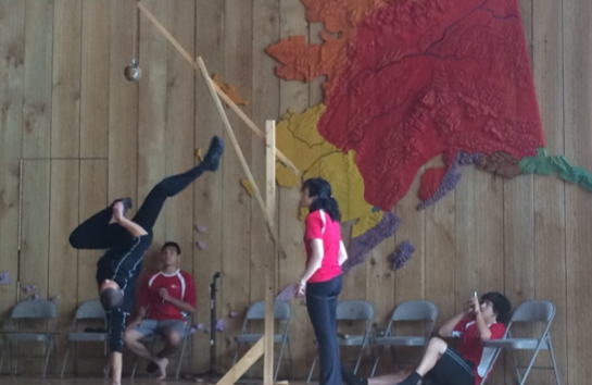 A dance is performed in a space with a map of Alaska and native territories in the background.