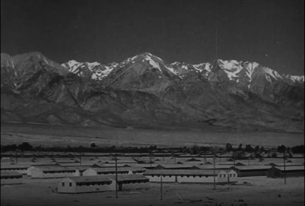 A still from The Japanese Relocation that shows Manzanar Relocation Center internment barracks set in the backdrop of the Inyo Mountains