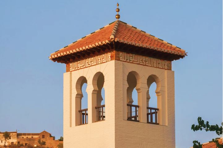 Photo of the minaret of the Grand Mosque of Granada, designed to blend into the preexisting architecture of the city's Moorish Quarter.