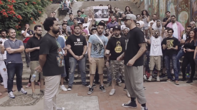 Ivorian-Lebanese rapper Edd Abbas on the left squares off against Lebanese-American rapper Dizaster on the right with Lebanon-based Syrian-Filipino rapper Chyno moderating in the center on the steps of the Mar Mkhayel neighborhood in East Beirut.