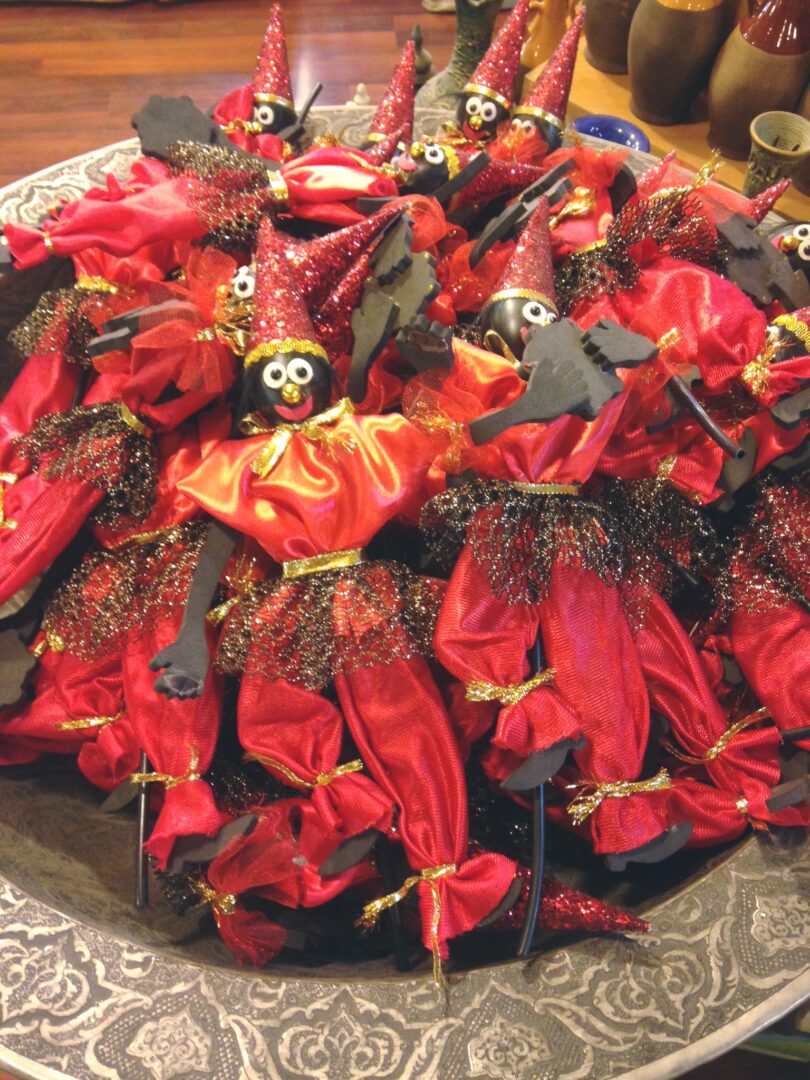 A pile of Haji Firuz dolls for sale as a Nowruz decoration in a novelty shop in Tehran. The dolls are dressed in red, with glitter cone-shaped hats, and their heads are fashioned out of a black ball and have googly eyes and thick red lips.