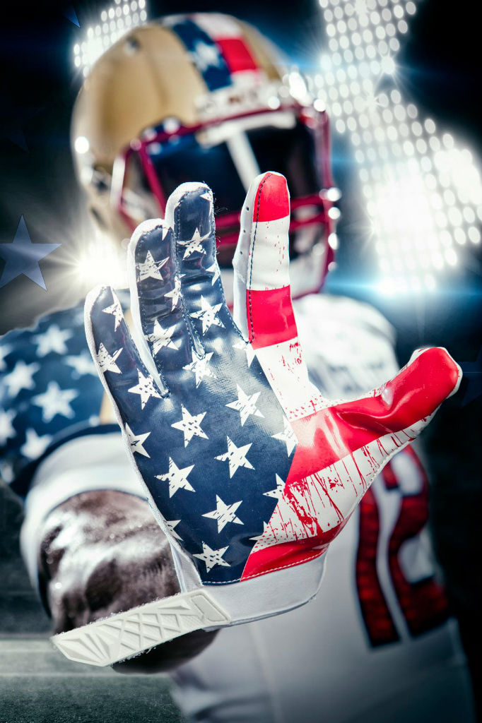 A football player in US-flag-themed jersey holds up his hand to the camera