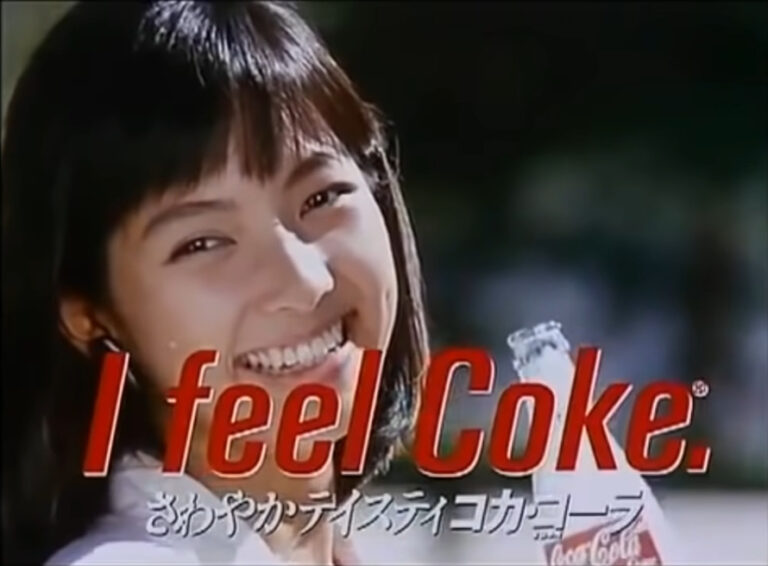 A woman holding a bottle of Coke and smiling at the viewer, while the text in the foreground reads "I feel Coke."