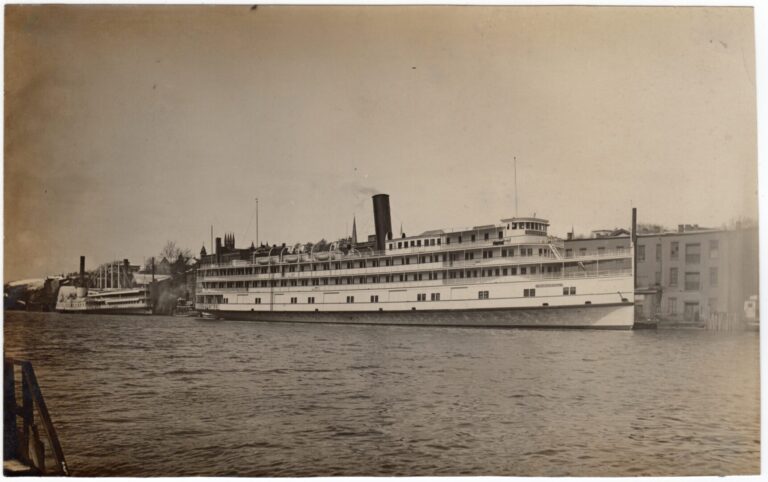 A photograph depicting the starboard side of a large steamboat docked at Rondout Creek near Newburgh, New York. Text near the bow of the boat identifies the vessel's name as "Benjamin B. Odell." Another steamboat, the Mary Powell, is docked behind it in the background of the photograph.