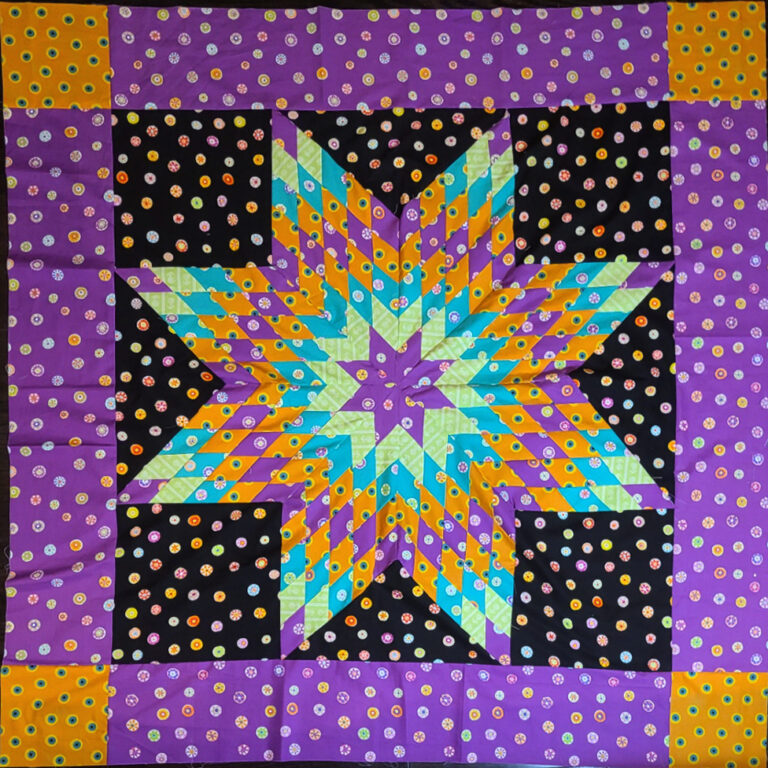 A star quilt with an eight-sided star at its center, composed of concentrically-colored diamonds, with multi-colored dots throughout.