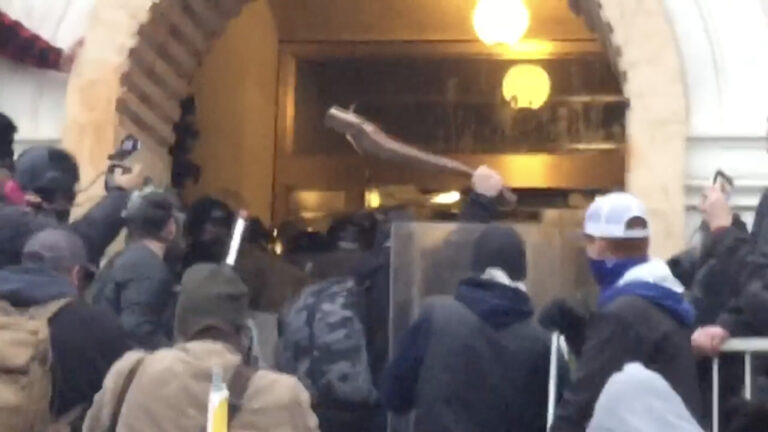 Still image from a video shared to Facebook on January 6, 2021 shows a crowd of participants in the US Capitol Riot assailing Capitol Police with various weapons, including a wooden plank with a protruding nail.