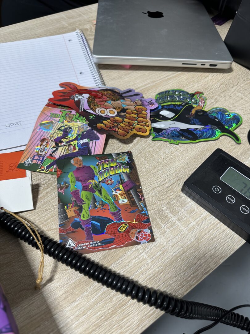 A photo of four cannabis packages on Wallace’s desktop, including a package for the strain “Blue Shamu,” featuring Grandpa Ted in cowboy boots and had riding a killer whale.