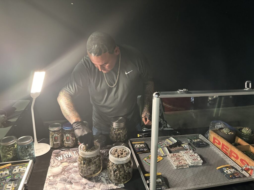 A cannabis vender picks buds out of a jar.