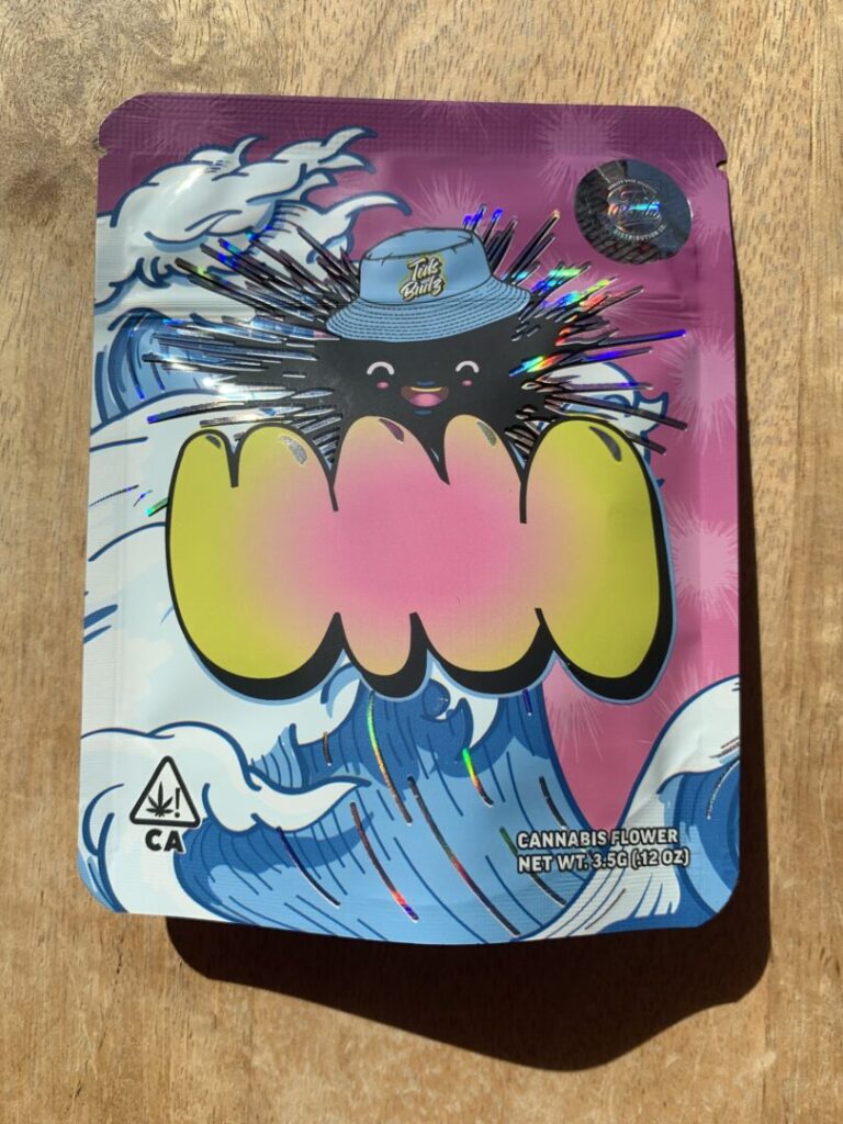 This package for the “Uni” strain features an anime-inspired spikey black sea urchin with large eyes and smiling mouth and wearing a baby-blue bucket hat with a white Teds Budz logo as they ride an ocean wave