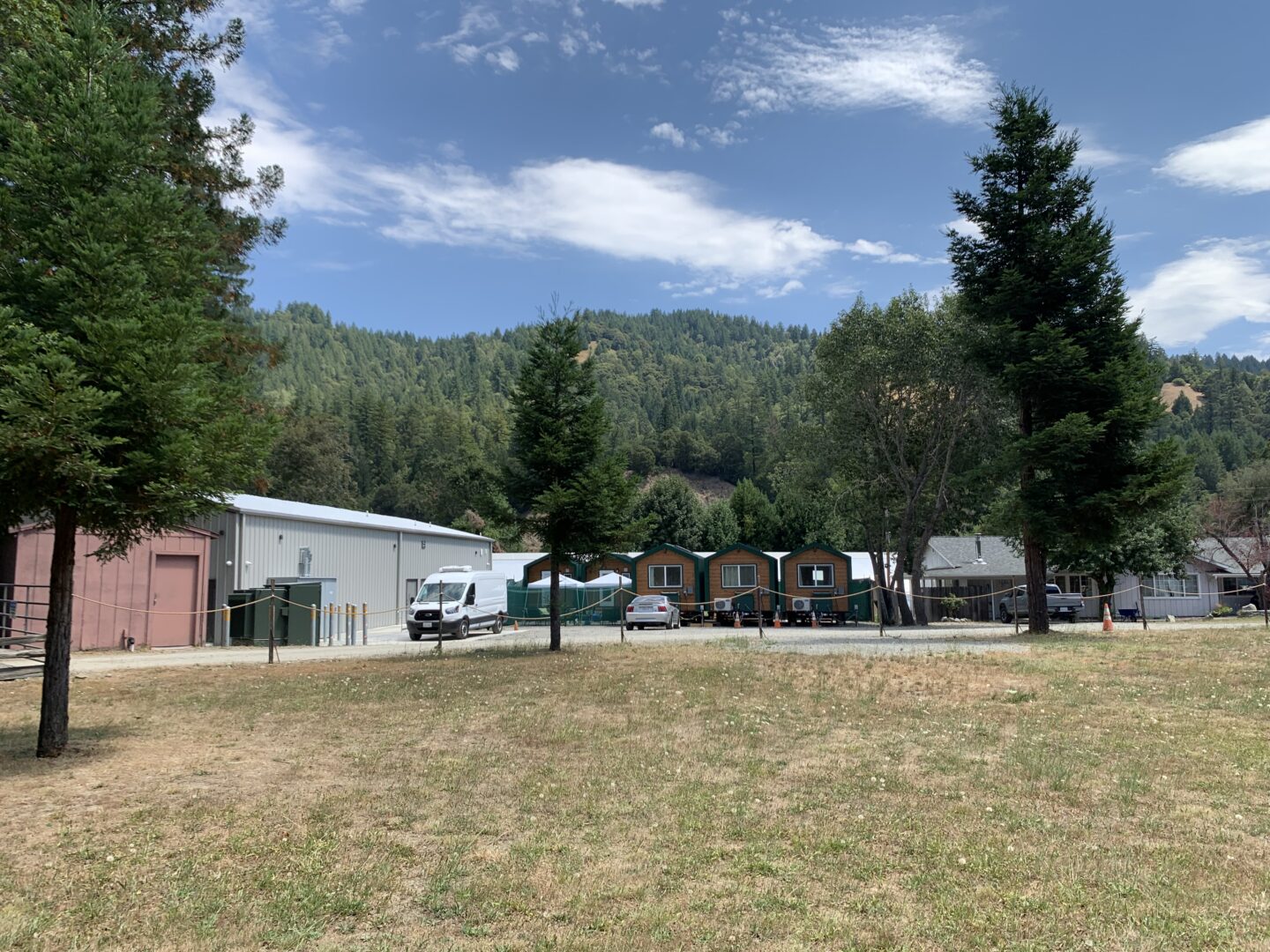 A row of tiny houses for “Cookies U” students at the One Log cannabis complex, a tree-covered mountain in the background. 