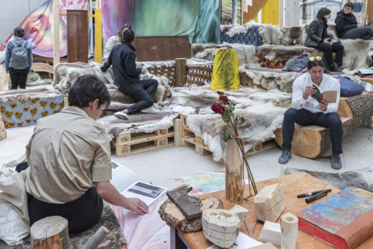 Visitors browsing books in an artistically arranged seating area featuring objects from the Sami culture.