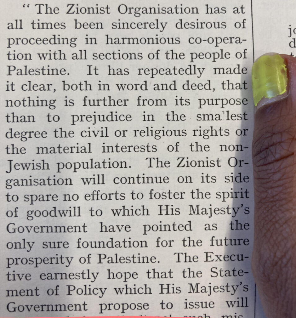 A page from a 1924 memorandum printed in black held by a finger with neon yellow nail polish. The visible text reads "The Zionist Organization has at all times been seriously desirous of proceeding in harmonious co-operation with all sections of the people of Palestine. It has repeatedly made clear, both in word and deed, that nothing is further from its purpose than to prejudice in the smallest degree the civil or religious rights or the material interests of the non-Jewish population. The Zionist Organization will continue on its side to spare no efforts to foster the spirit of goodwill to which His Majesty's Government have pointed as the only sure foundation for the future prosperity of Palestine. The Executive earnestly hope that the Statement of Policy which His Majesty's Government propose to issue will..."