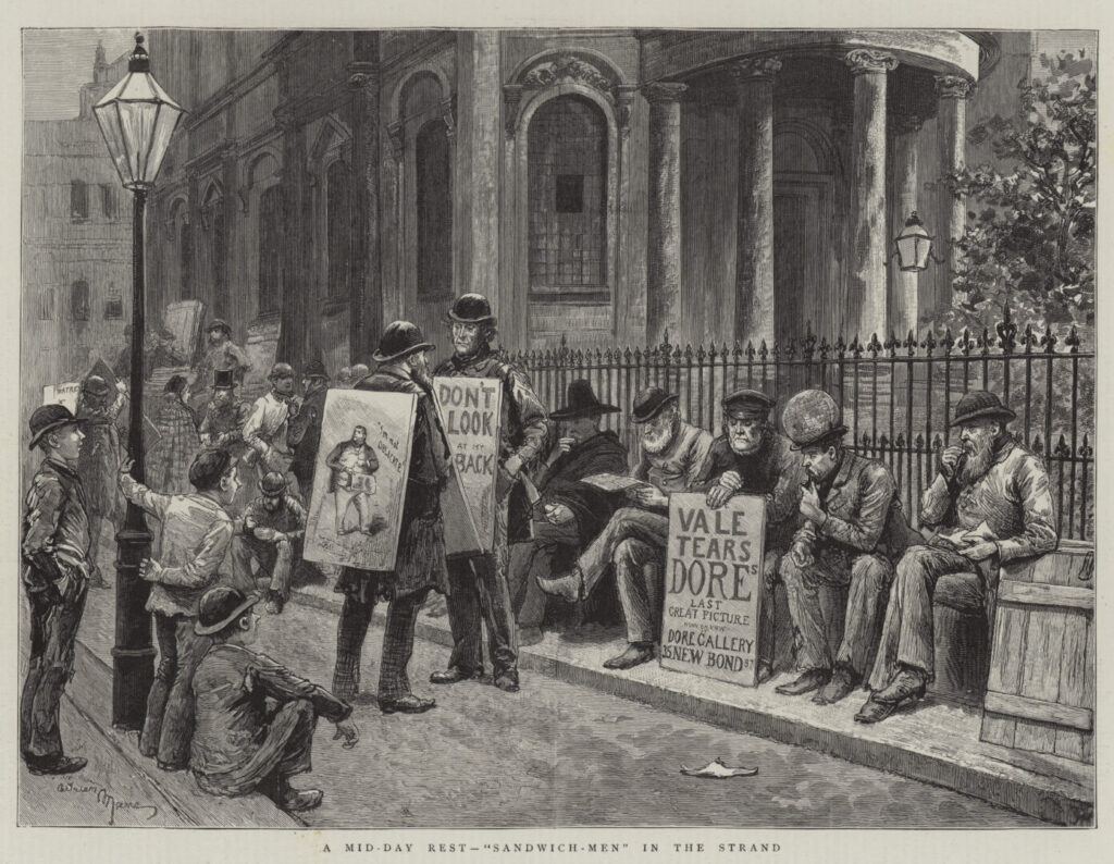 An engraving from 1884 showing the Strand in London with men sitting along a fence. The men are wearing suits and costumes and are holding or wearing sandwichboards with various advertisements on them. Three younger boys are observing the sandwichmen from a streetlamp.