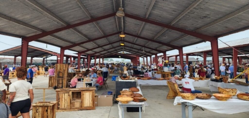 Outdoor hobbycraft stalls displaying various handcrafted woodwork items, including furniture and decorative objects, for sale to the public.