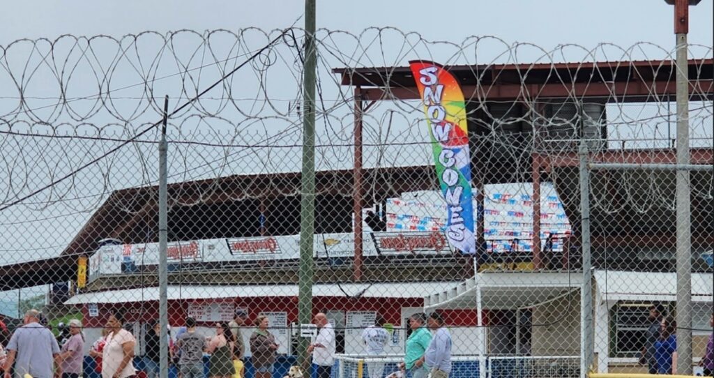 A food stall behind a chain-link fence topped with coils of barbed wire.