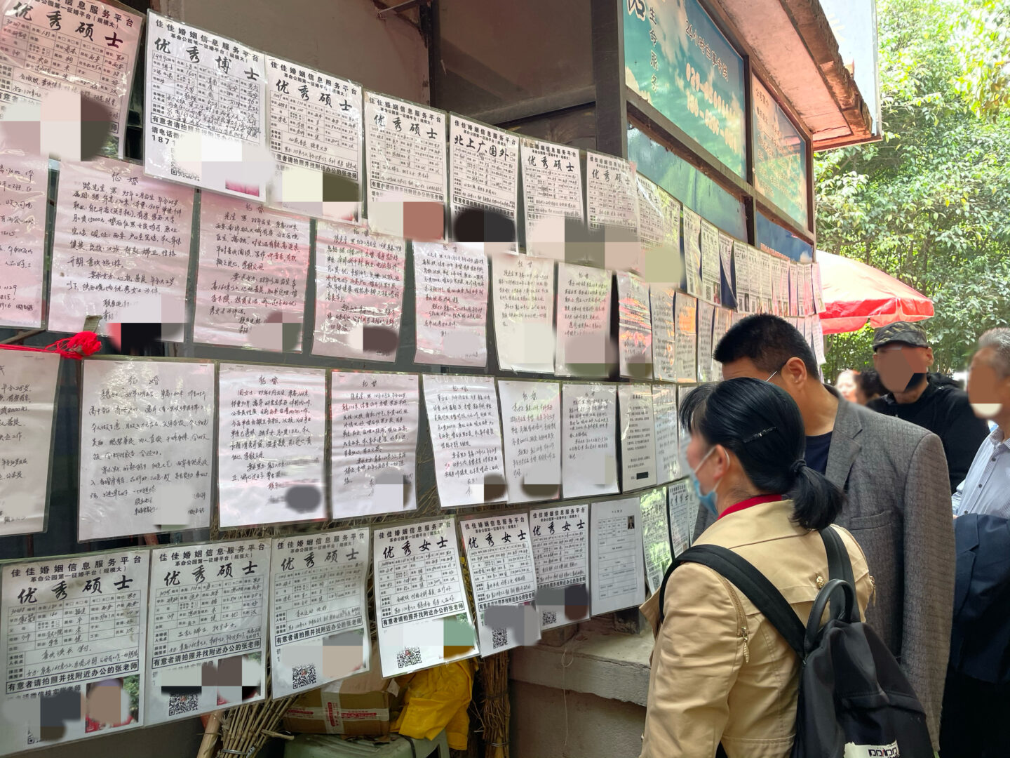 Photo of people reading notices in Chinese on a bulletin board.