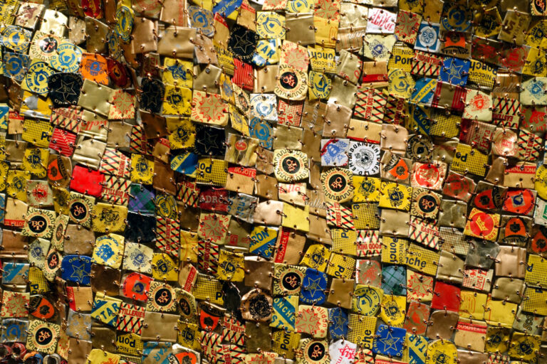 Photo of El Anatsui's "Many Came Back. Aluminum liquor bottle tops and copper wire, 84 x 115 inches (Newark Museum)
