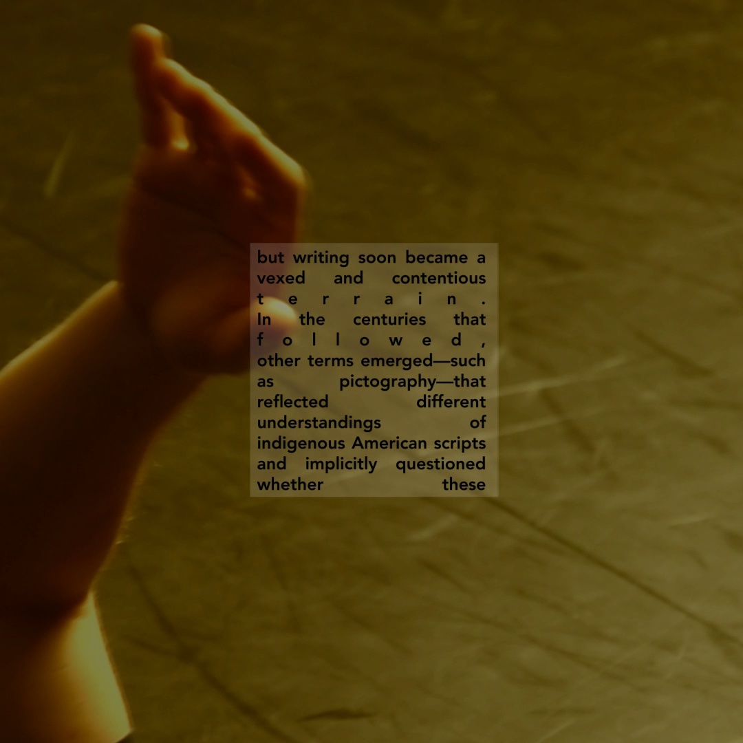 Only the hand is visible, of an apparently white figure lying in an empty studio. Colorshift sepia. Overlaid text on the status of colonial writing and indigenous American scripts.