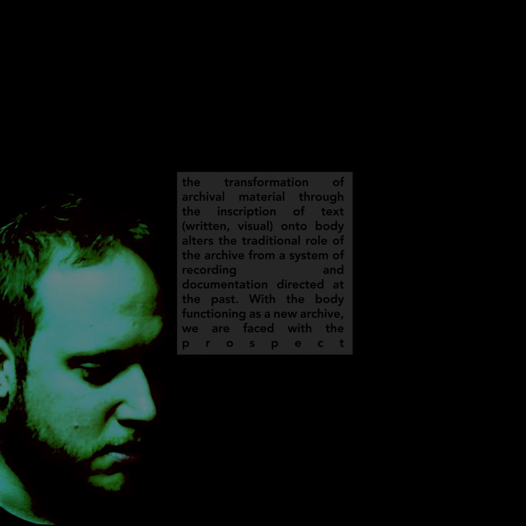 An apparently white figure stands in an empty studio, looking down, their body out of frame. Colorshift green. Overlaid text on the archive, documentation, and writing.