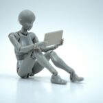 Plastic marionette seated reading a tablet computer.